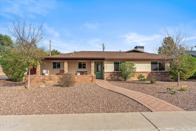 ranch-style house with covered porch, brick siding, and stucco siding