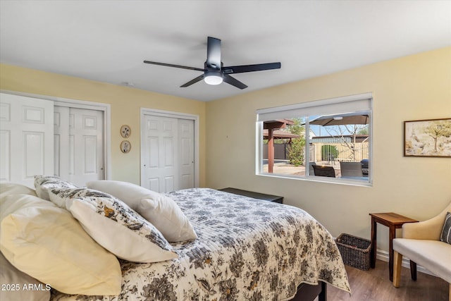 bedroom with a ceiling fan, wood finished floors, and two closets