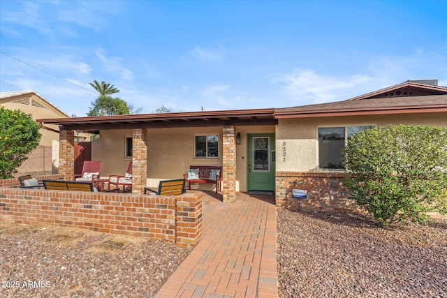 ranch-style home with brick siding, an outdoor hangout area, a patio, and stucco siding