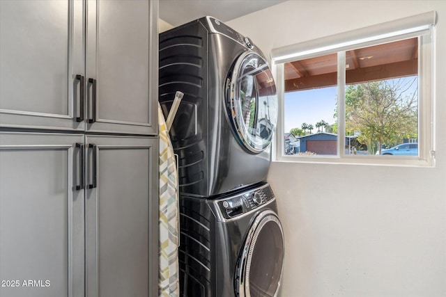 clothes washing area with stacked washer and clothes dryer and cabinet space