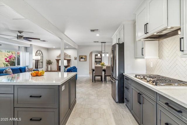 kitchen featuring open floor plan, stainless steel appliances, arched walkways, and gray cabinets