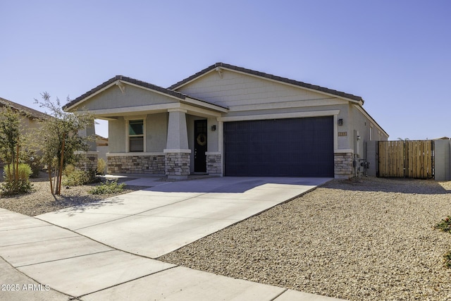 view of front of property with driveway, stone siding, an attached garage, a gate, and stucco siding