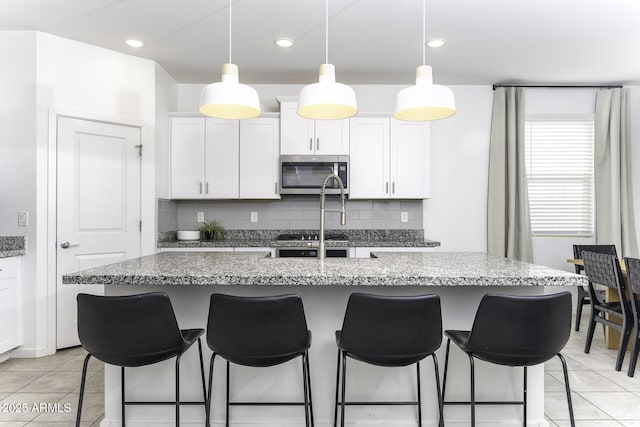 kitchen featuring white cabinets, stainless steel microwave, and a breakfast bar