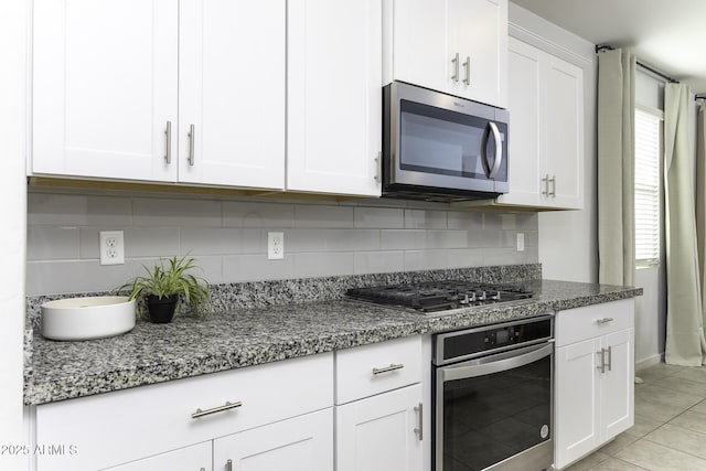 kitchen featuring light tile patterned floors, white cabinetry, stainless steel appliances, and backsplash