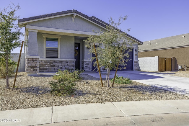 view of front of home with a garage, concrete driveway, stone siding, and stucco siding