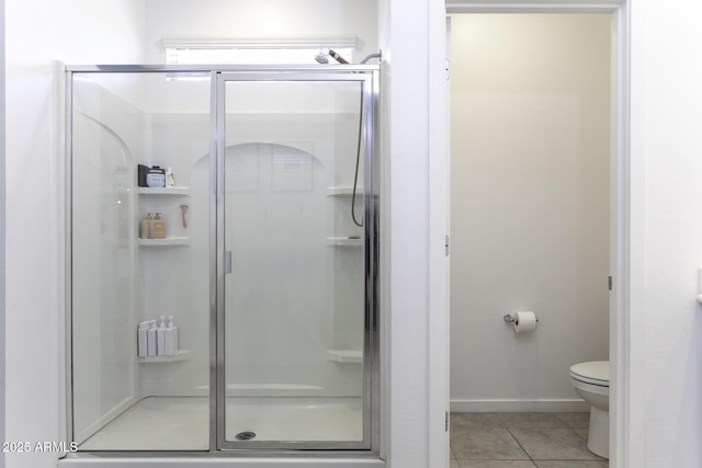 full bath featuring toilet, a stall shower, baseboards, and tile patterned floors