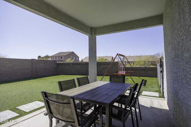 view of patio featuring outdoor dining space, a playground, and a fenced backyard