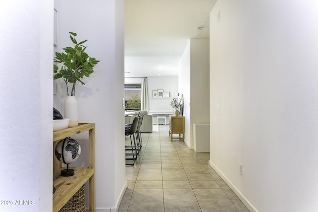 hallway featuring baseboards and light tile patterned floors