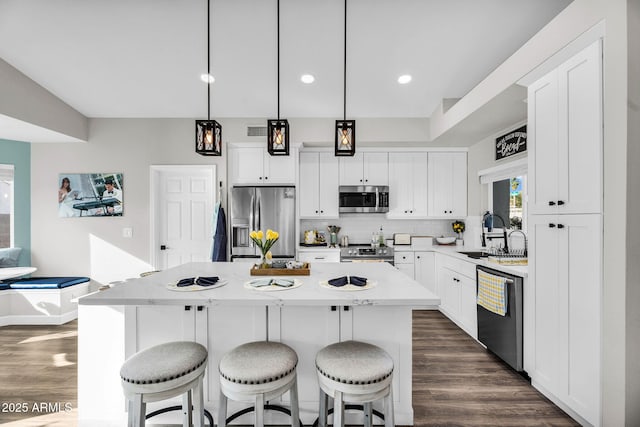 6145 E Snowdon St, Mesa, AZ 85215 - kitchen featuring appliances with stainless steel finishes, a sink, a kitchen island, dark wood-style flooring, and a breakfast bar