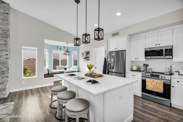 6145 E Snowdon St, Mesa, AZ 85215 - kitchen with stainless steel appliances, a kitchen island, decorative backsplash, a breakfast bar area, and white cabinetry