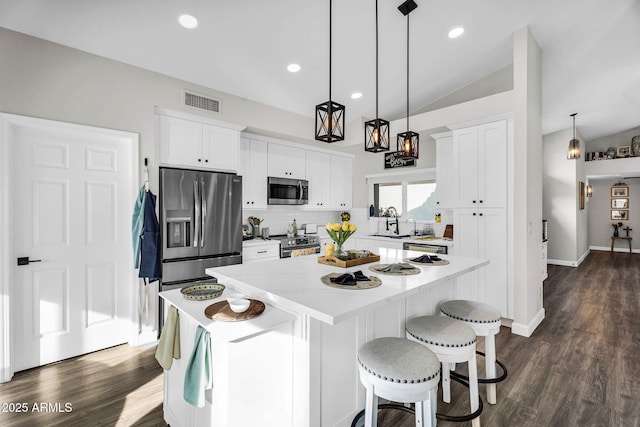 6145 E Snowdon St, Mesa, AZ 85215 - kitchen with appliances with stainless steel finishes, a kitchen island, vaulted ceiling, backsplash, and white cabinetry