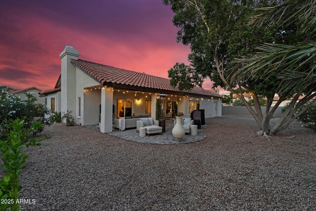 6145 E Snowdon St, Mesa, AZ 85215 - back of house at dusk featuring an outdoor hangout area, stucco siding, a tile roof, a patio area, and a chimney