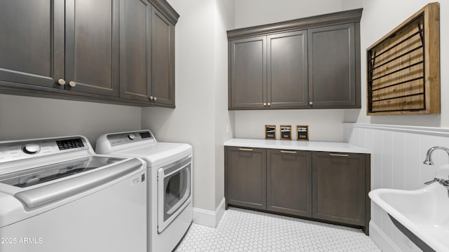 clothes washing area with cabinets, washing machine and clothes dryer, and sink