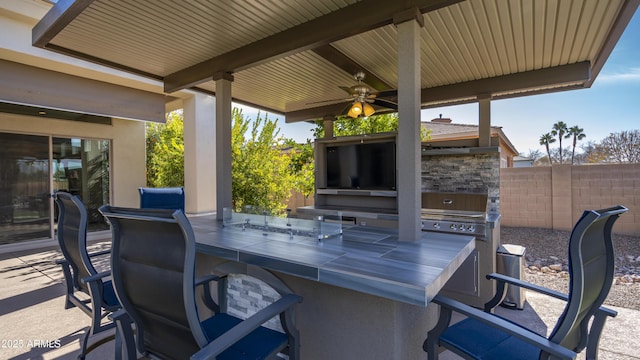 view of patio with area for grilling, an outdoor bar, ceiling fan, and an outdoor kitchen