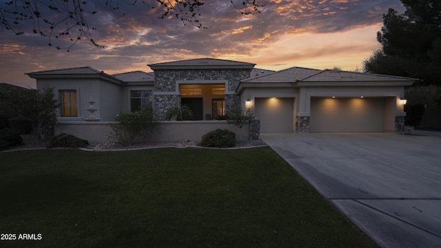 prairie-style home featuring a garage and a yard