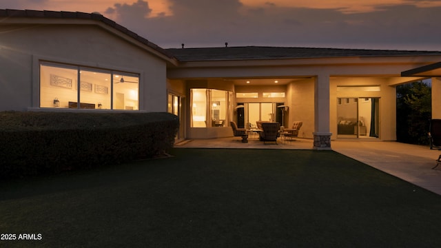 back house at dusk with a patio