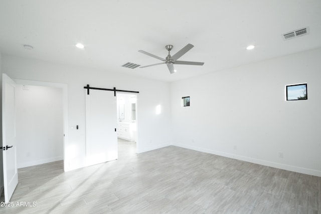 unfurnished room featuring ceiling fan and a barn door