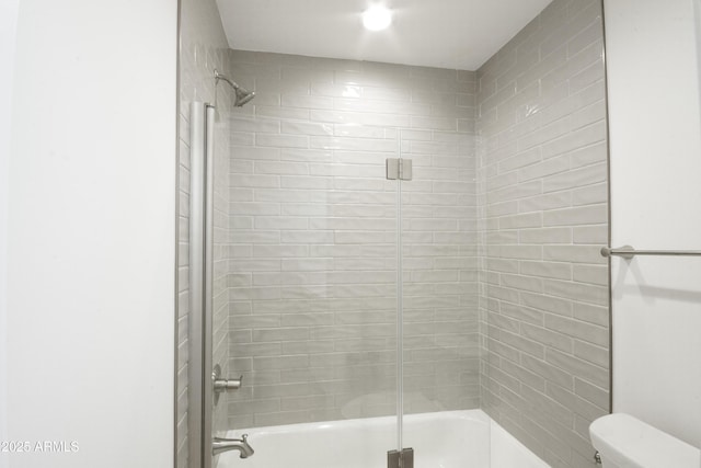 bathroom featuring combined bath / shower with glass door and toilet