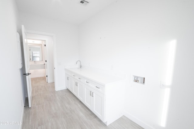 clothes washing area with washer hookup, sink, and light hardwood / wood-style flooring