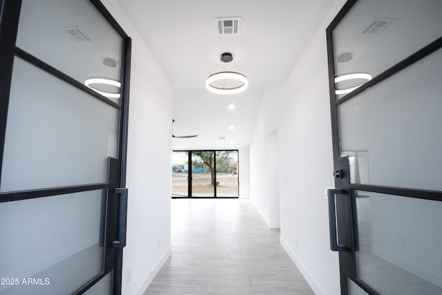 hallway with expansive windows and light wood-type flooring