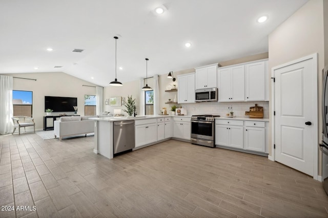 kitchen with appliances with stainless steel finishes, pendant lighting, light hardwood / wood-style flooring, and white cabinets