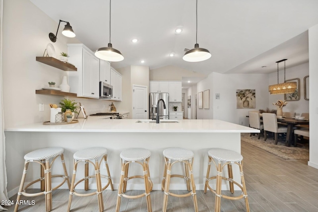 kitchen featuring light hardwood / wood-style floors, hanging light fixtures, stainless steel appliances, and white cabinets