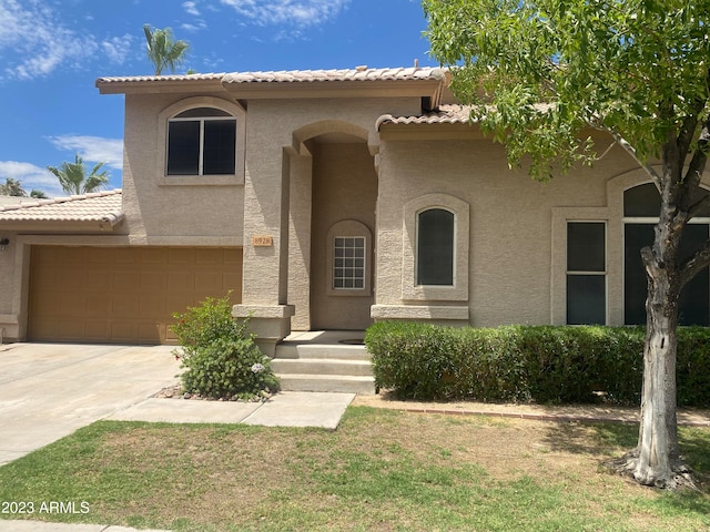 mediterranean / spanish-style home with a garage and a front lawn