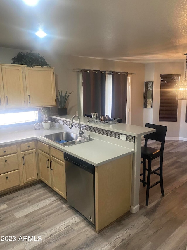 kitchen with light wood-type flooring, dishwasher, kitchen peninsula, and sink