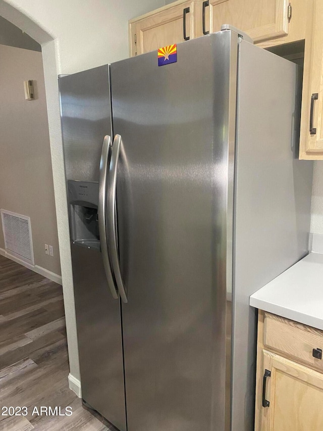 kitchen with wood-type flooring, light brown cabinets, and stainless steel fridge