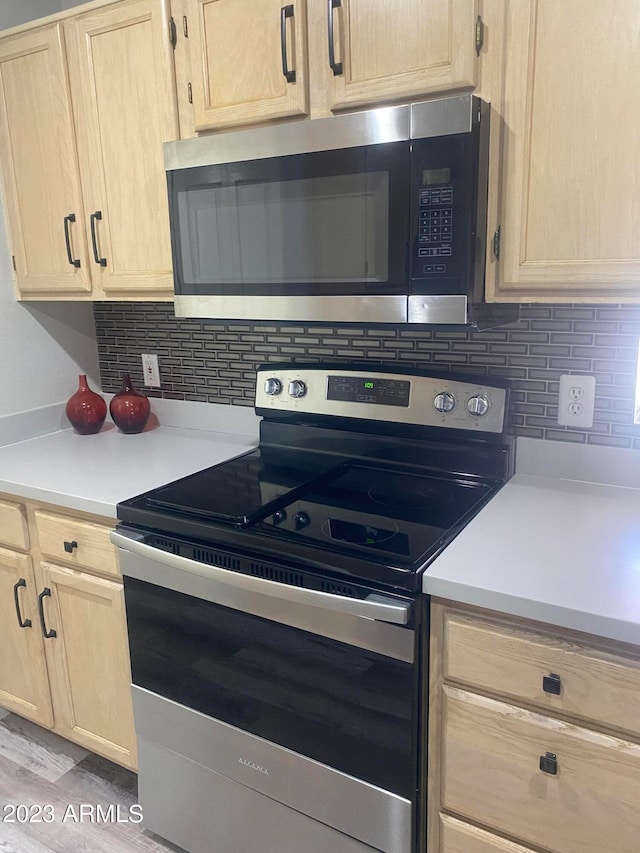 kitchen with appliances with stainless steel finishes, light hardwood / wood-style floors, and light brown cabinetry