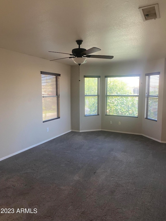 carpeted spare room featuring a textured ceiling and ceiling fan