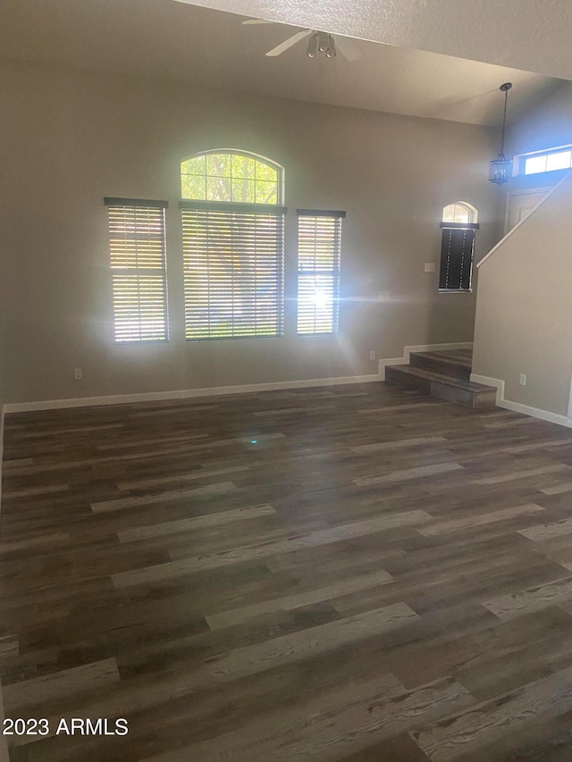 unfurnished living room with ceiling fan and dark wood-type flooring