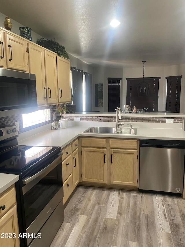 kitchen featuring decorative backsplash, light hardwood / wood-style floors, appliances with stainless steel finishes, and sink