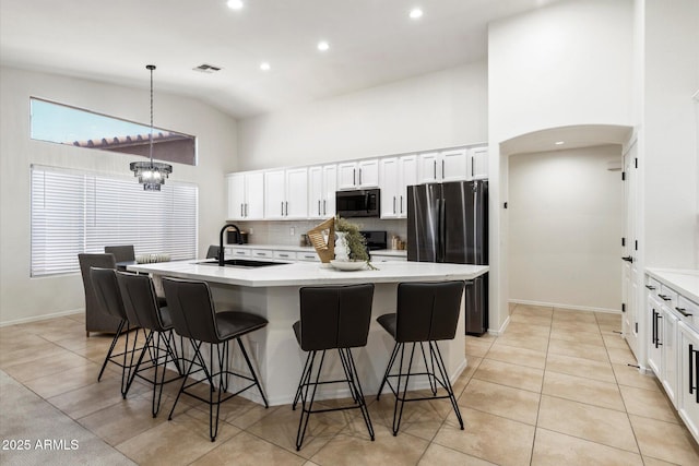 kitchen with sink, high vaulted ceiling, stainless steel fridge, an island with sink, and pendant lighting