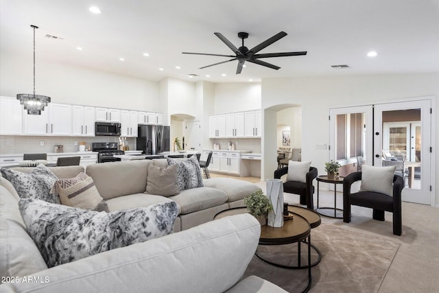 living room featuring ceiling fan with notable chandelier and high vaulted ceiling