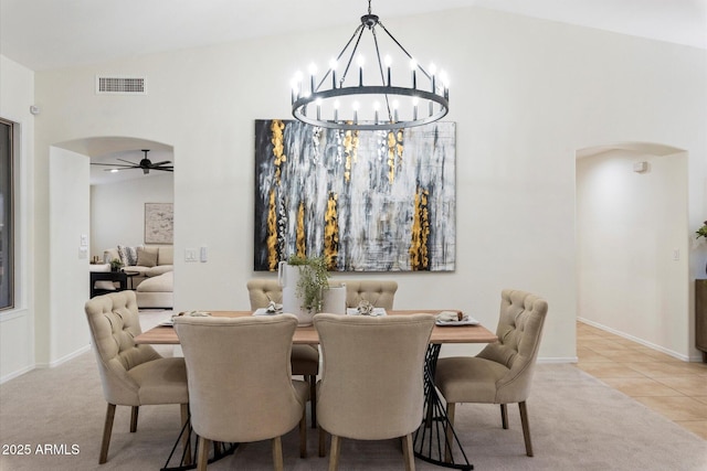 dining area featuring ceiling fan with notable chandelier, vaulted ceiling, and light tile patterned floors