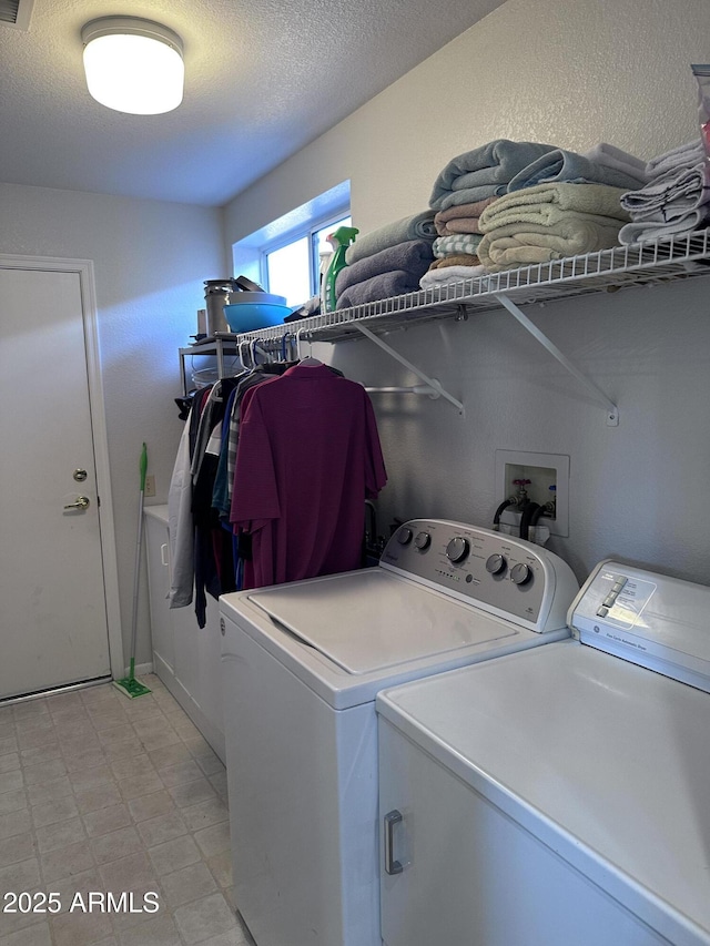 clothes washing area with a textured ceiling and independent washer and dryer