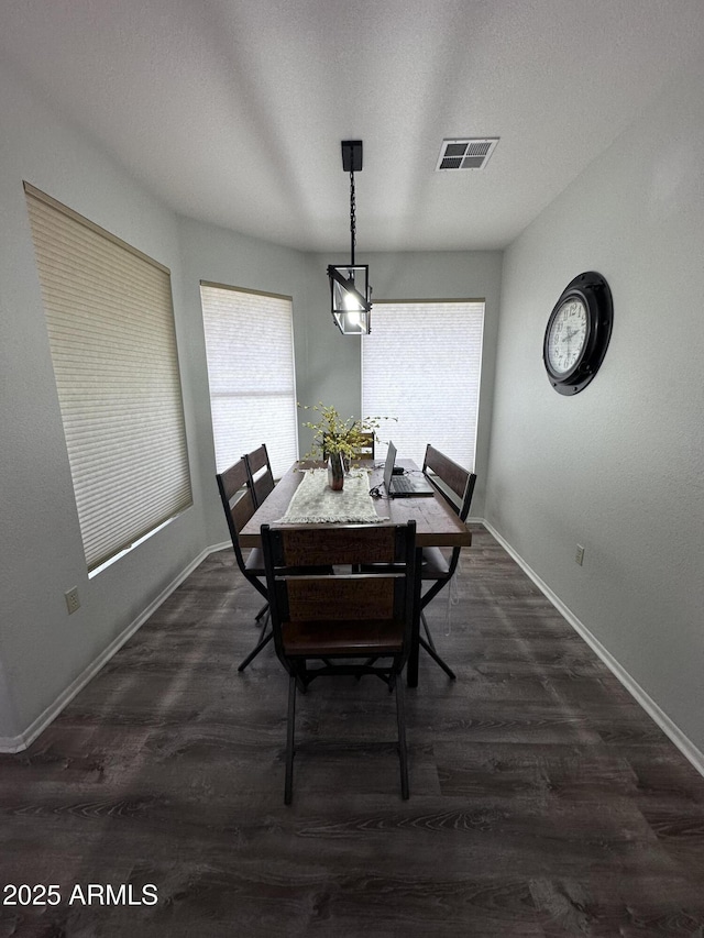 dining space with plenty of natural light, dark hardwood / wood-style floors, and a textured ceiling