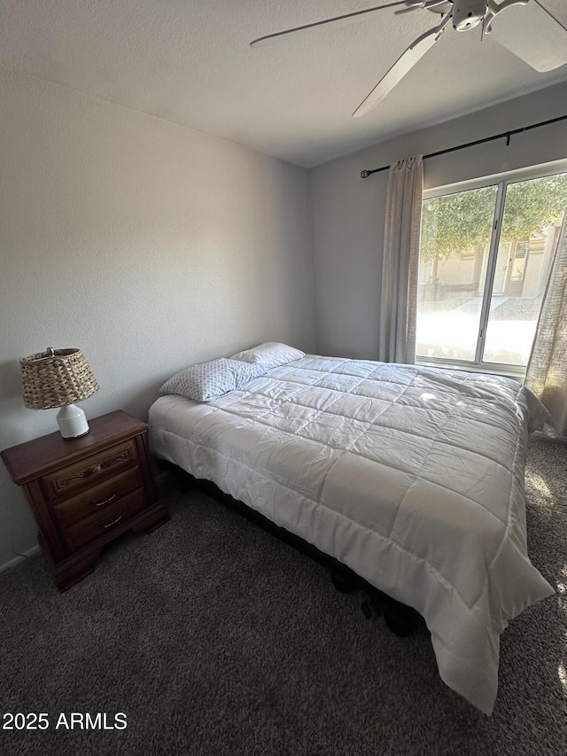 carpeted bedroom featuring ceiling fan and a textured ceiling