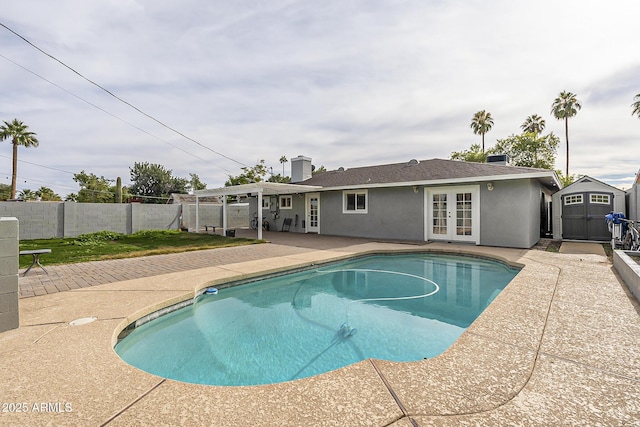 view of swimming pool featuring french doors, a storage shed, and a patio area