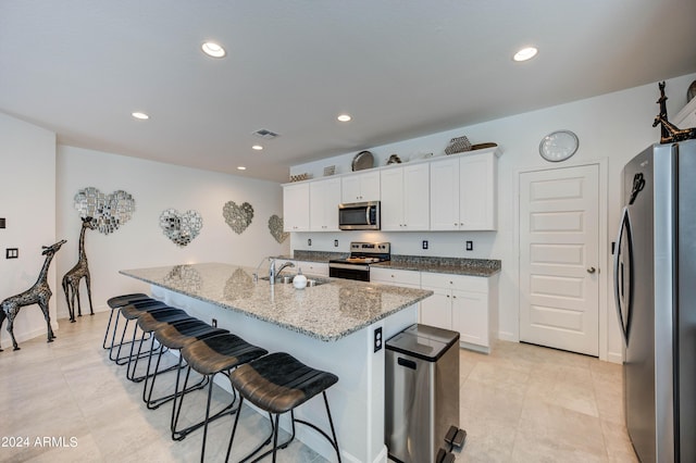 kitchen featuring white cabinetry, stainless steel appliances, a kitchen island with sink, and a breakfast bar area