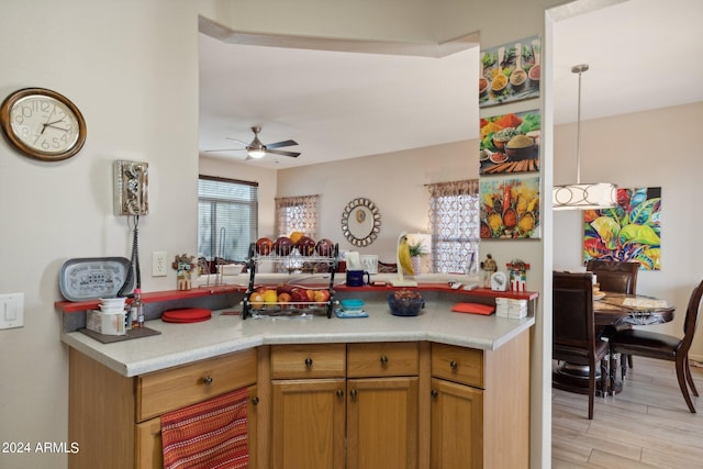 kitchen with kitchen peninsula, light wood-type flooring, ceiling fan, and hanging light fixtures