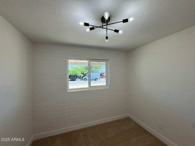 empty room featuring baseboards, dark carpet, and a textured ceiling
