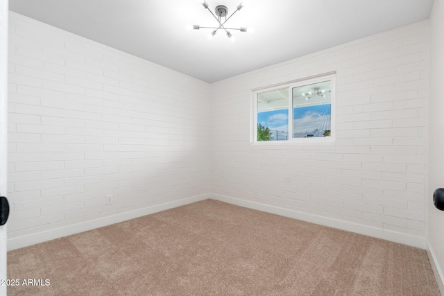 empty room featuring carpet floors, baseboards, and a notable chandelier