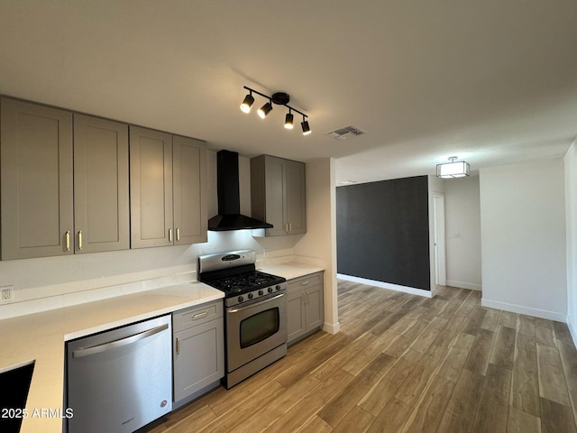 kitchen featuring stainless steel appliances, visible vents, wall chimney exhaust hood, light countertops, and gray cabinetry
