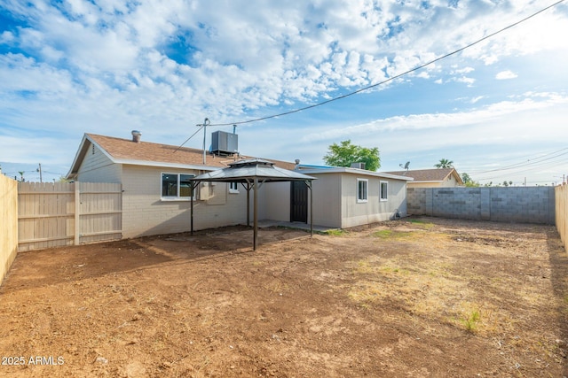 rear view of property featuring a fenced backyard, a gazebo, and central air condition unit