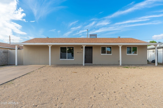 ranch-style home with roof with shingles and fence