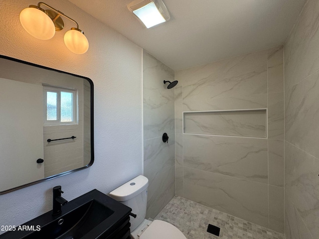 full bathroom featuring vanity, toilet, and tiled shower