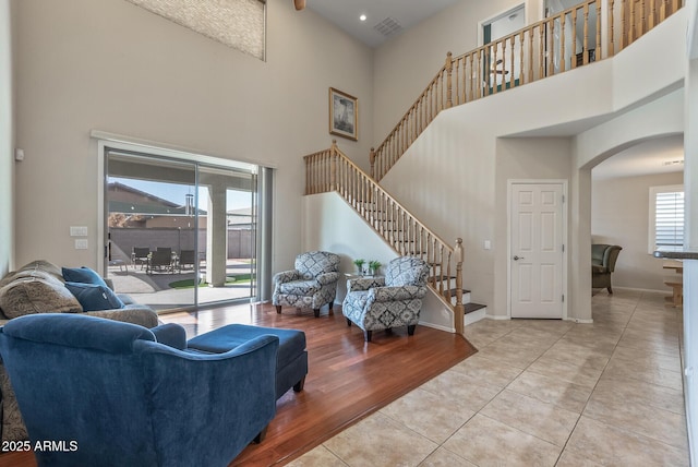 living area with visible vents, a high ceiling, light tile patterned floors, baseboards, and stairs