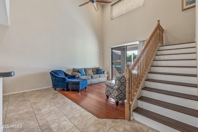 interior space with tile patterned flooring, baseboards, ceiling fan, stairway, and a towering ceiling